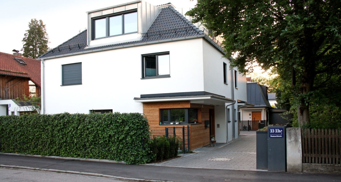 Modernes Wohnhaus mit weißer Fassade, Holzverkleidung und Dachgaube – Damaschkestraße 33 (Straßenansicht mit Einfahrt und Hecke)