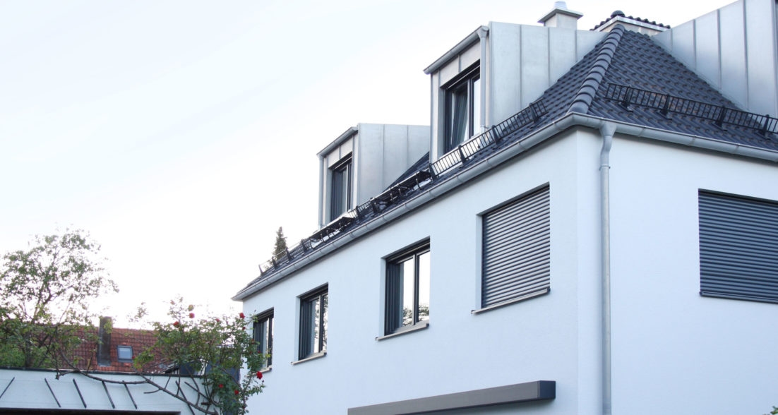 Damaschkestraße 33 – Fassadendetail: weiße Putzfassade mit Rollläden, Ziegeldach und Dachgauben (Schrägansicht)